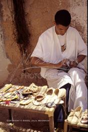 Image du Maroc Professionnelle de  Un artisan marocain fabrique des chaussures, de chapeaux de paille, et de vannerie en raphia, une fabrication artisanale faite main dont la production est très prisée par la population. Son Atelier se situe dans une rue à l'ancienne Kasbah de  Ouarzazate où résident les berbères du sud du Maroc, le Vendredi 22 Août 1997. (Photo / Abdeljalil Bounhar)

